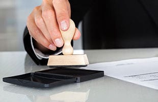 A person is using a rubber stamp on a table.