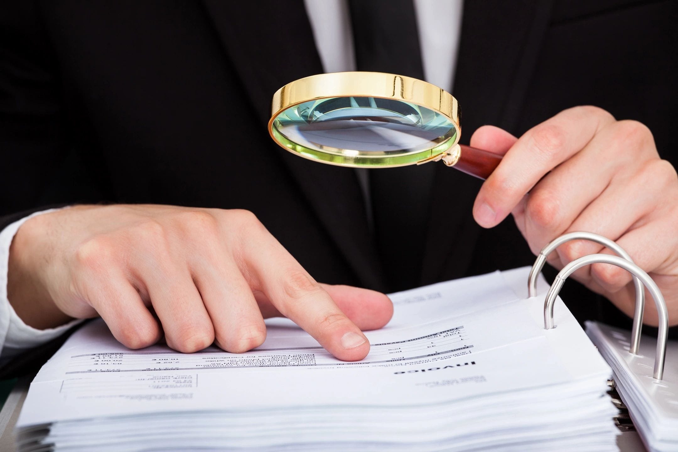 LiveScan 2 Go A person holding a magnifying glass over papers.