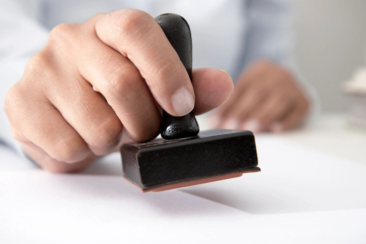 LiveScan 2 Go A person is using a rubber stamp to seal the paper.